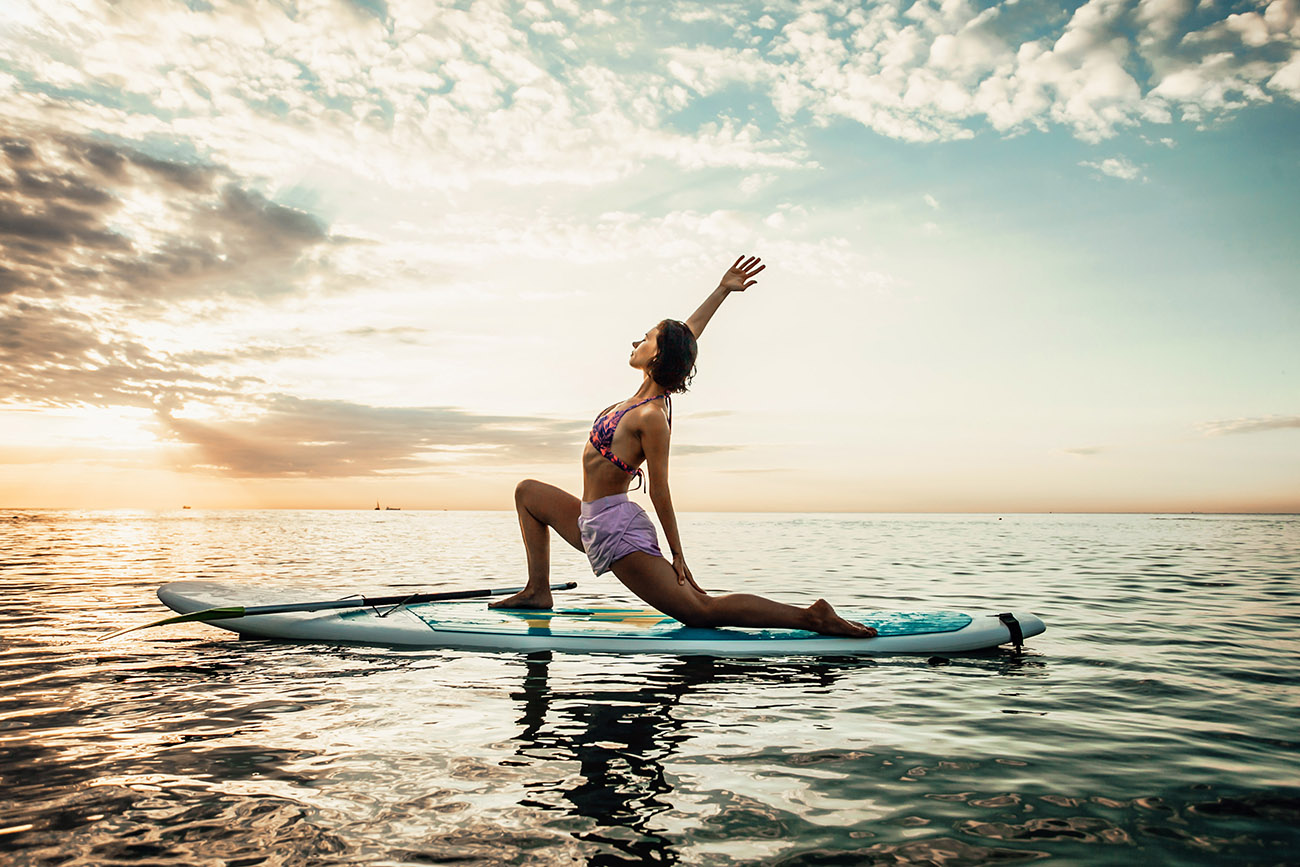 young woman doing yoga on a sup board in the lake AA9L8RX
